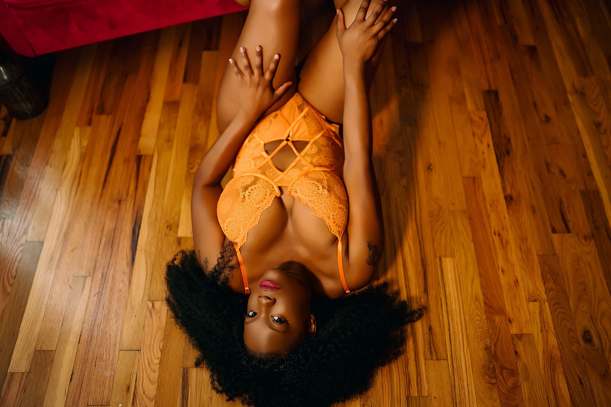 African american woman in orange lace bodysuit laying on hardwood floor Fort Worth Lanora Ronee Photography