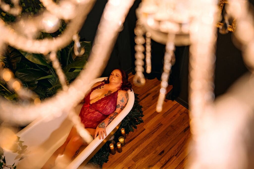 Plus size woman laying in 1912 clawfoot tub with plants and a chandelier Fort Worth Lanora Ronee Photography