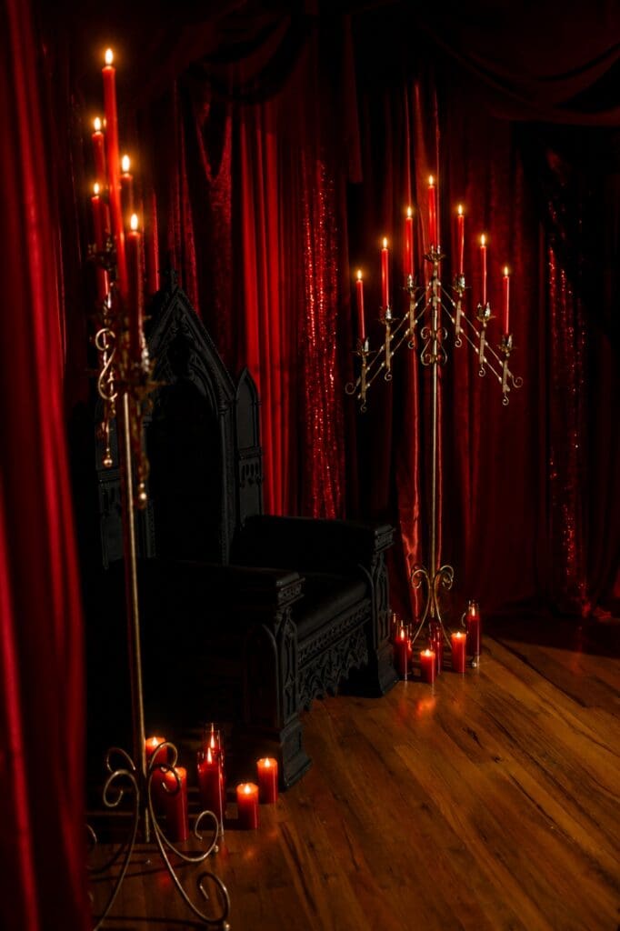 Gothic boudoir photography set with black throne, red velvet draping, candles and antique candelabras in Fort Worth Texas.